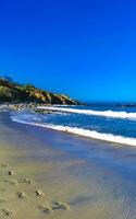 skön stenar klippor surfare vågor på strand puerto escondido Mexiko. foto