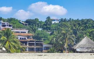 palmer parasoller Sol solstolar strand vågor puerto escondido Mexiko. foto