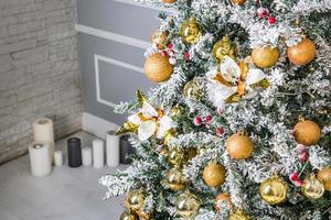 dekorerad julgran med gyllene ornament och ljus i bakgrunden