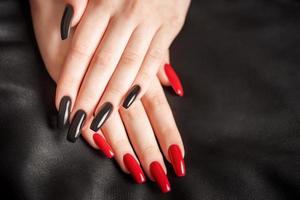 händer av en ung flicka med svart och röd manikyr på naglar foto