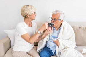 fru tar vård av henne sjuk make.senior man har influensa. gammal människor, senior man med vinter- säsong- sjukdom, feber, kall foto