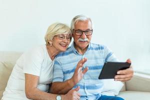 senior par använder sig av digital läsplatta på Hem. farföräldrar använder sig av social media. äldre par tillsammans på Hem pensionering begrepp använder sig av digital läsplatta foto