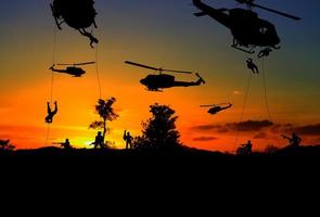 silhuett soldater rappel ner till ge sig på från helikopter med krigare akta sig fara på de jord solnedgång bakgrund fläck och kopia Plats Lägg till text foto