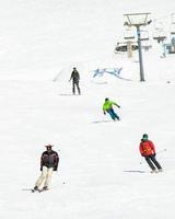 fyra vänner skidåkare pensionärer främre se åka skidor utför på Semester i åka skidor tillflykt ha roligt tillsammans i bergen foto