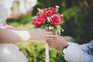 brudgummen ger bukett till bruden med naturbakgrund