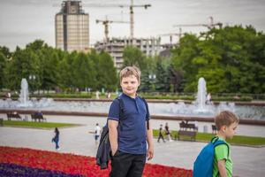 porträtt av en barn, en pojke mot de bakgrund av urban landskap av skyskrapor och höghus byggnader i de öppen luft. barn, resa. livsstil i de stad. Centrum, gator. foto