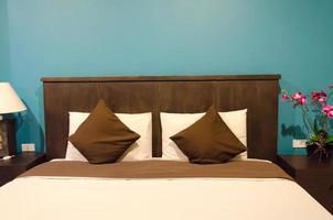 kuddar på en brun säng i ett blått rum