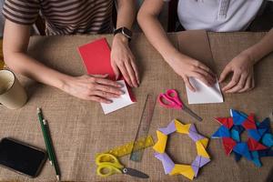 mamma och dotter göra origami från färgad papper på självisolering foto