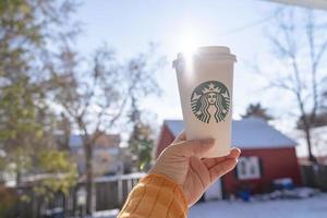 marinette, wi, usa - 14 nov, 2019- koppar av starbucks varm kaffe sätta på vit snö i vinter- trädgård, färsk och varm dryck ta bort concept.starbucks Kafé kaffe affär. foto