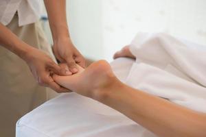 närbild av massage terapeut massera kvinnliga ben på spa salong foto