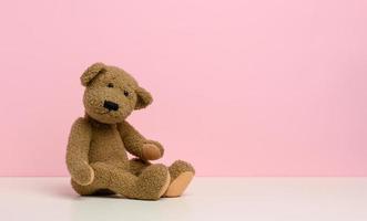 brun teddy Björn med plåster sitter på en vit tabell, rosa bakgrund foto