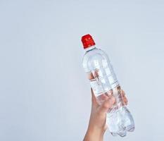 transparent plast flaska med färsk vatten i en kvinna hand foto
