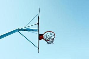 gammal övergiven gata basketboll ring och blå himmel bakgrund foto