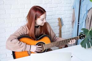 ung kvinna inlärning till spela gitarr på Hem foto