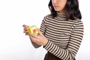 asiatisk kvinna innehav en rubik kub stående på vit bakgrund. lösning kubisk problem, problem lösning och framställning strategisk rör sig begrepp foto