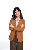 ung asiatisk kvinna, professionell businness entreprenör i brun kostym med vapen korsade och leende isolerat över vit bakgrund foto