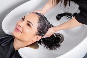 professionell frisör tvättning hår av ung kvinna i skönhet salong.. stänga upp av kvinnas hår i skönhet salong, frisyr begrepp foto