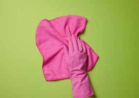 hand i en rosa sudd handske innehar en mjuk trasa för rengöring ytor på en vit bakgrund foto