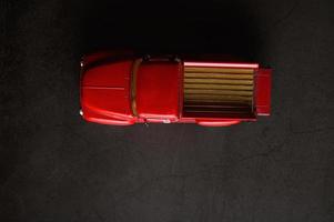röd pickup modell lastbil på ett svart golv
