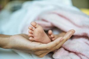 nyfödda baby fötter på mors hand foto