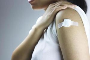 asiatiska kvinnor har ett bandage på axeln efter en vaccininjektion foto