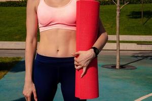 elegant sportig flicka stänga upp abdominal muskler i händer Träning matta foto
