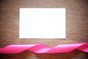 rosa band med vitt tomt papper på trä