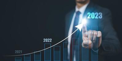 affärsman Rör tillväxt data Diagram pil med diagram 2023 budget, affärsman pekande pil Graf företags- framtida tillväxt år 2022 till 2023, utveckling till Framgång och motivering. foto