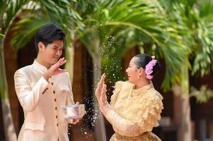ung par stänk vatten från skål på songkran festival foto