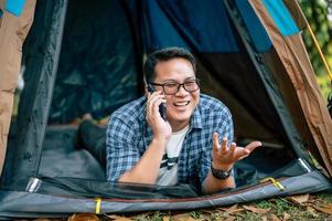porträtt av Lycklig asiatisk resande man glasögon liggande i tält camping foto