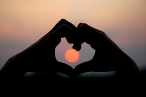hjärta formad mänsklig hand silhuett solnedgång bakgrund foto