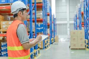 asiatisk man företag ägare använder sig av checklista kontrollera igen belopp av stock produkt lager på hylla på distribution lager fabrik.logistik företag fartyg och leverans, lager flöde, professionell. foto