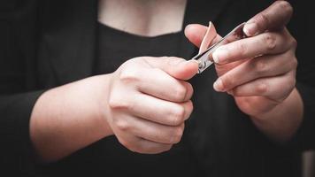 handen på en vit kvinna som klipper hennes naglar med nagelklippare. begreppet hygien. foto