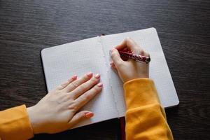 kvinna skriver i tom anteckningsbok. närbild av hand som håller penna. foto