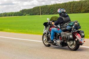 motorcyklist rider längs de väg på en sommar solig dag. cyklist på en motorcykel. foto