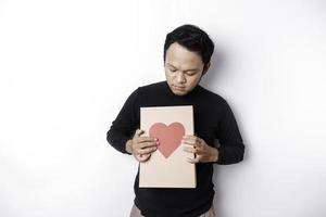 skön ung asiatisk man bär svart skjorta innehav gåva låda röd hjärta, hjärtans dag begrepp. foto