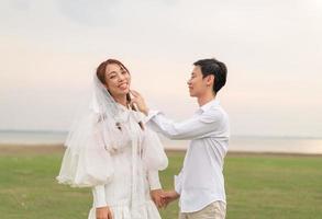 lyckliga unga asiatiska par i brud och brudgum kläder foto