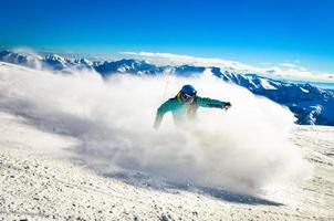 professionell skidåkare på full hastighet åka skidor utför på färsk snö do träsnideri i åka skidor tillflykt medan Träning för konkurrens i åka skidor tillflykt med bergen bakgrund foto