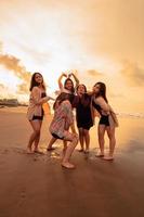 en grupp av indonesiska kvinnor njut av de strand lyckligt när de träffa deras vänner på de Semester ögonblick foto