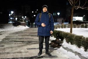 man turist med ryggsäck i de natt stad på vinter. foto