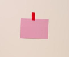tom rektangulär rosa ark av papper limmad på en ljus blå bakgrund. plats för ett inskrift, meddelande foto