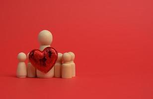 trä- små figurer av en familj och en röd hjärta på en röd bakgrund foto