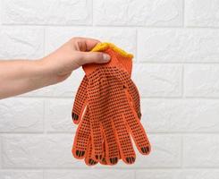 kvinna hand innehar textil- orange arbete handskar på en vit bakgrund foto