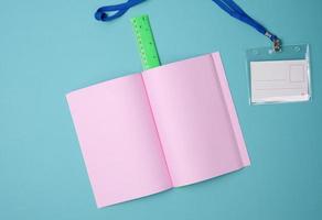 öppen anteckningsbok med tom rosa lakan, linjal på blå bakgrund, topp se foto