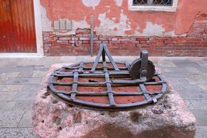 stänga upp gammal vatten väl med järn grill i Italien. gata scen, gammal vägg. foto