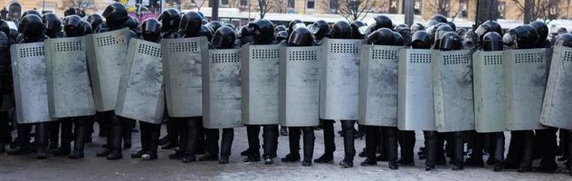 linje av polis upplopp krafter, protest i stad. enhetlig rustning med sköldar foto