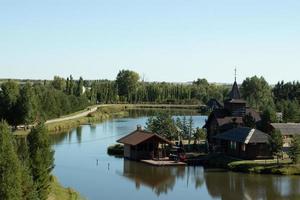 sjö hus i en trädbevuxen område. landsbygden liv, bruka nära flod. landskap foto