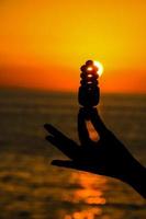 hand innehav en glödlampa på solnedgång foto