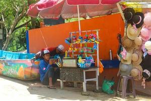 yogyakarta, indonesien i november 2022. män på baron strand vem arbete som hatt och leksak handlare sälja olika typer av strand hattar foto