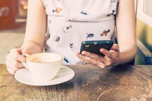 stänga upp av händer kvinna använder sig av telefon i kaffe affär med djup av fält foto